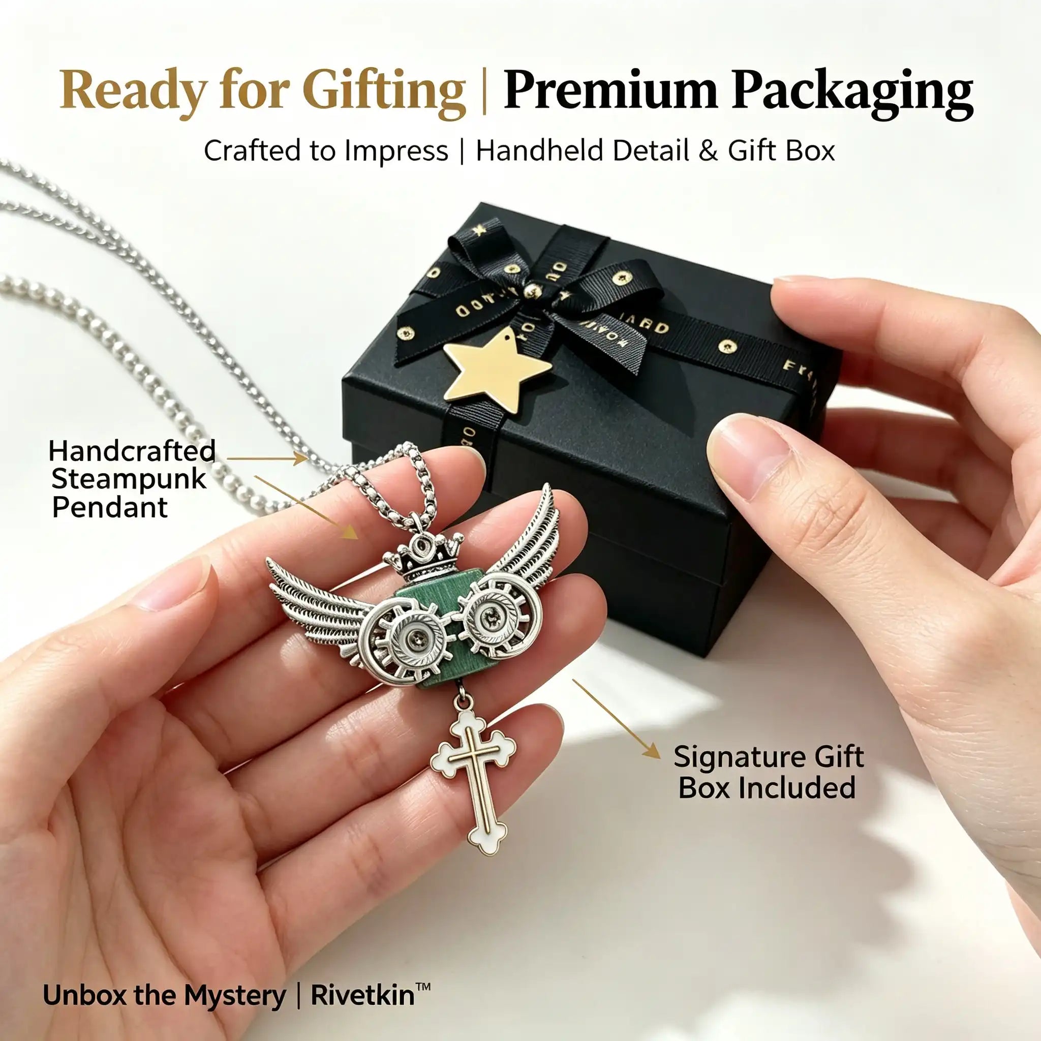 Handheld view of Rivetkin™ Steampunk Owl Winged Cross Pendant Necklace displayed next to a black premium gift box, highlighting real-world scale and gift packaging details.