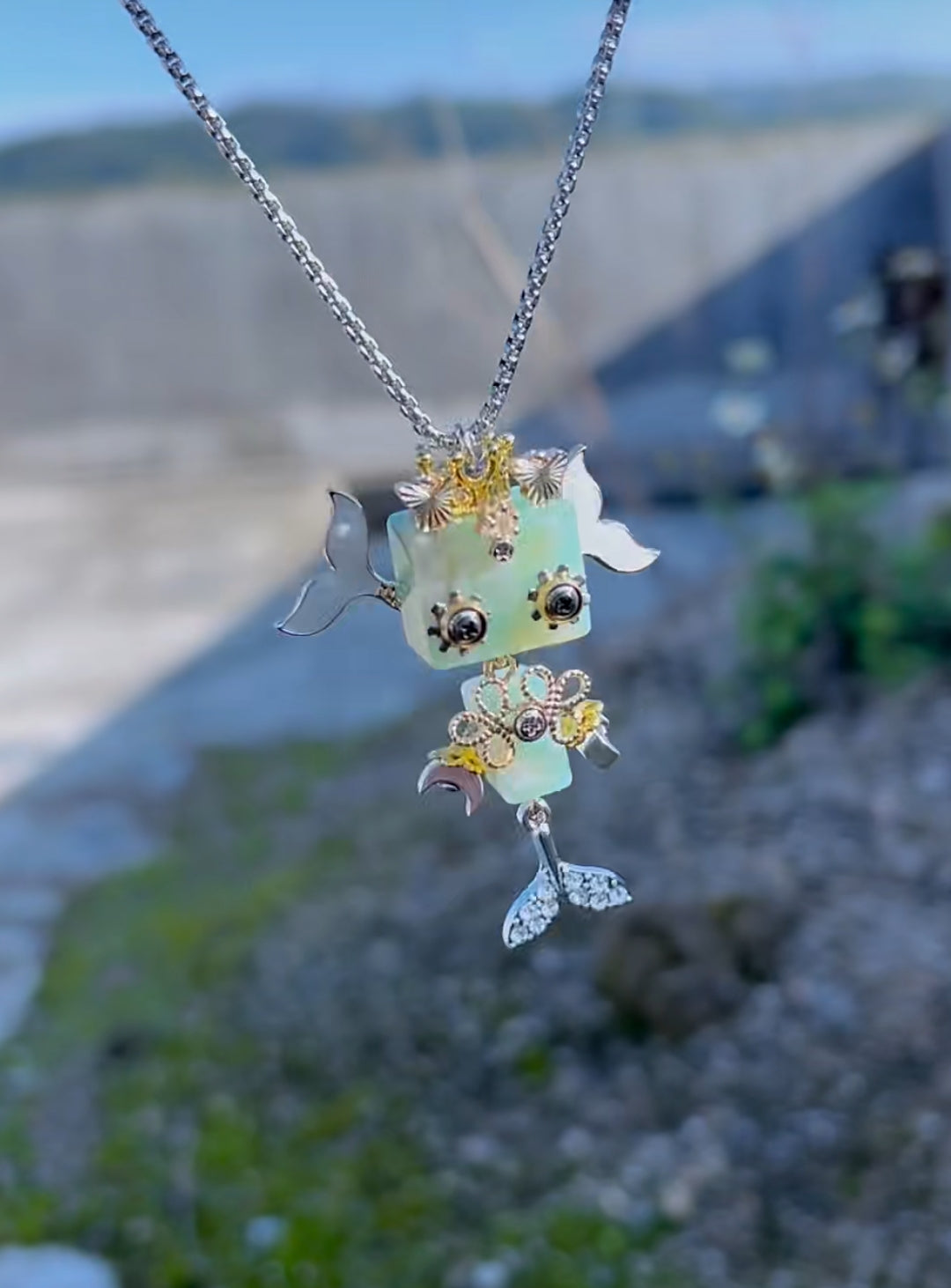 A handmade pale green Rivetkin robot pendant worn on a silver chain
